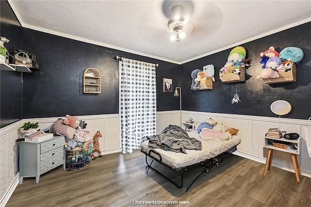 bedroom with wood-type flooring, a textured ceiling, ceiling fan, and ornamental molding