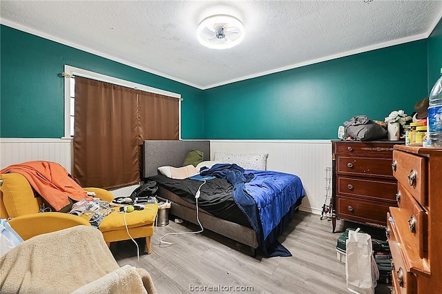 bedroom with light hardwood / wood-style floors, crown molding, baseboard heating, and a textured ceiling