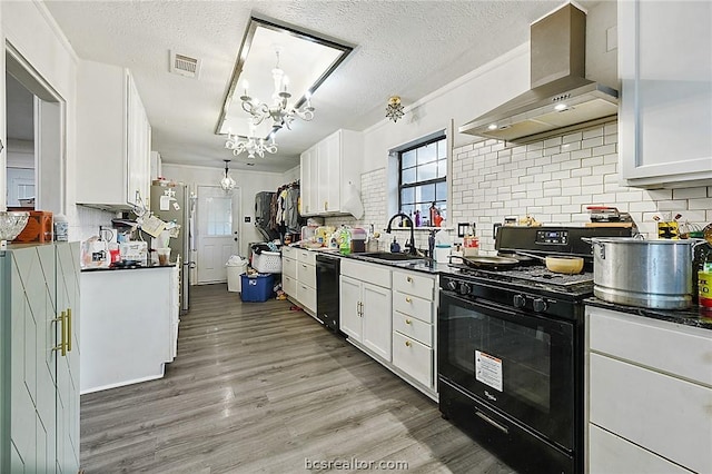 kitchen with white cabinetry, sink, wall chimney exhaust hood, pendant lighting, and black appliances