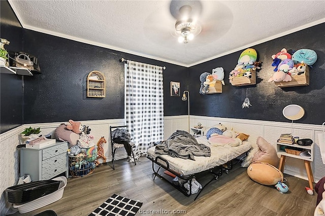 bedroom featuring ceiling fan, hardwood / wood-style floors, crown molding, and a textured ceiling