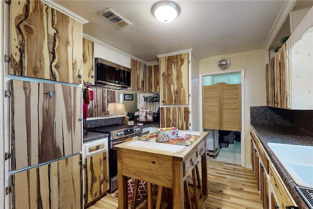 kitchen featuring light wood finished floors, visible vents, appliances with stainless steel finishes, ornamental molding, and a sink