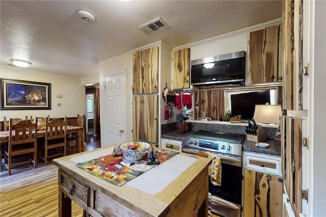 kitchen with visible vents, appliances with stainless steel finishes, light wood-type flooring, dark countertops, and crown molding