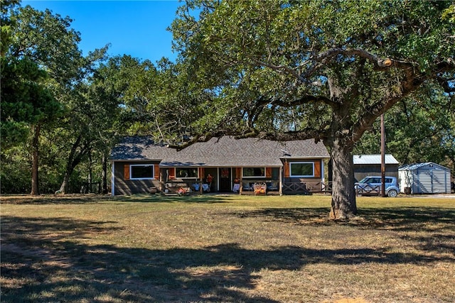 single story home featuring a front yard, a storage unit, and an outdoor structure