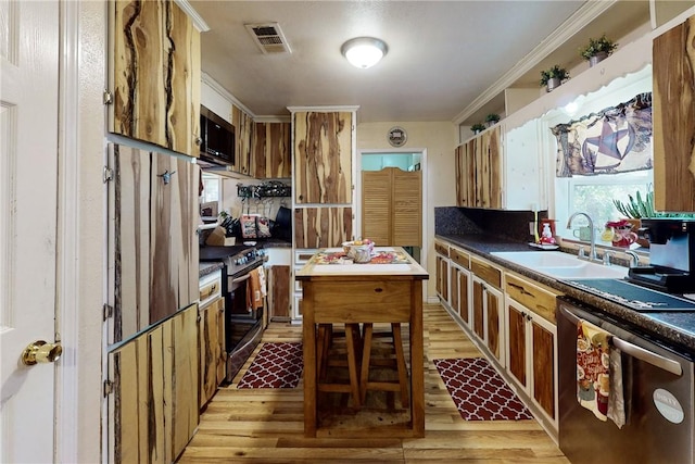 kitchen with crown molding, light wood finished floors, stainless steel appliances, visible vents, and a sink