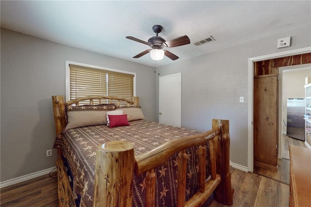 bedroom with baseboards, visible vents, stainless steel refrigerator, and wood finished floors