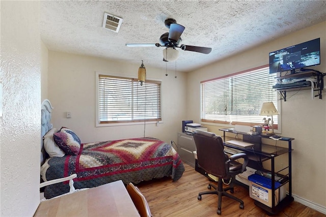 bedroom with baseboards, visible vents, ceiling fan, wood finished floors, and a textured ceiling