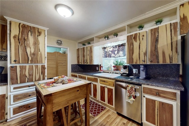 kitchen featuring light wood finished floors, decorative backsplash, dark countertops, stainless steel dishwasher, and a sink