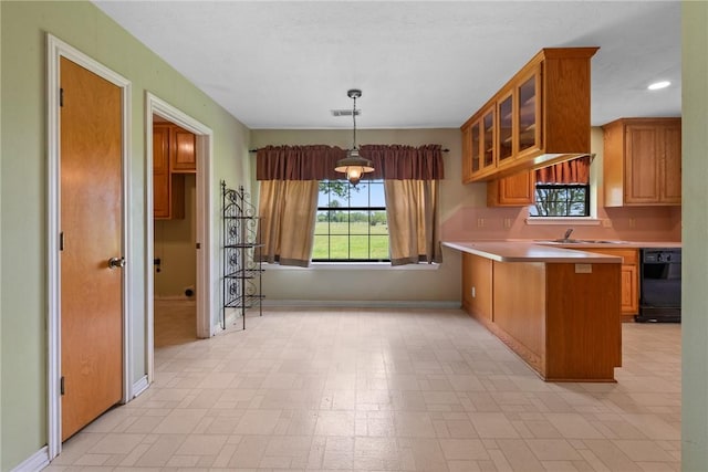 kitchen featuring light countertops, baseboards, a peninsula, black dishwasher, and glass insert cabinets