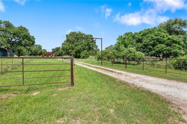 view of gate featuring a rural view, a yard, and fence