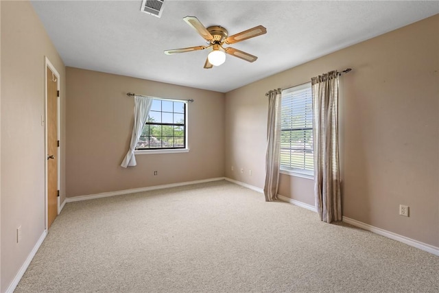 empty room featuring ceiling fan, light carpet, visible vents, and baseboards