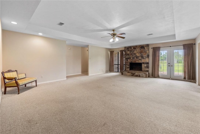 unfurnished living room with a tray ceiling, carpet, visible vents, and ceiling fan