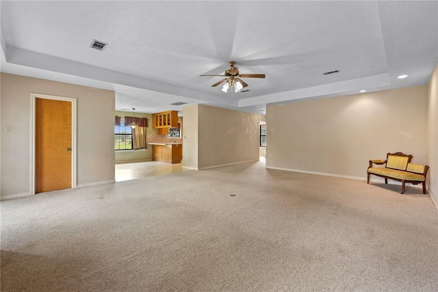 unfurnished living room featuring visible vents, baseboards, and a tray ceiling
