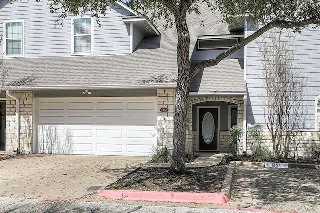 view of front of house with stone siding, roof with shingles, driveway, and an attached garage