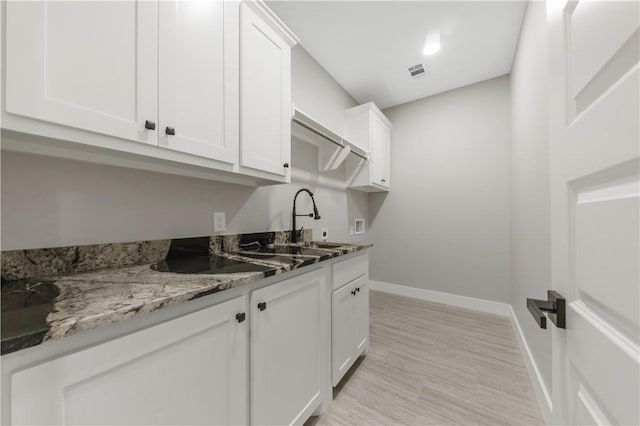2916 Bombay Ct, Bryan, TX 77808 - kitchen with white cabinets, baseboards, light stone counters, and a sink