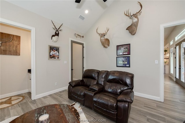 living room with ceiling fan, vaulted ceiling, and light wood-type flooring