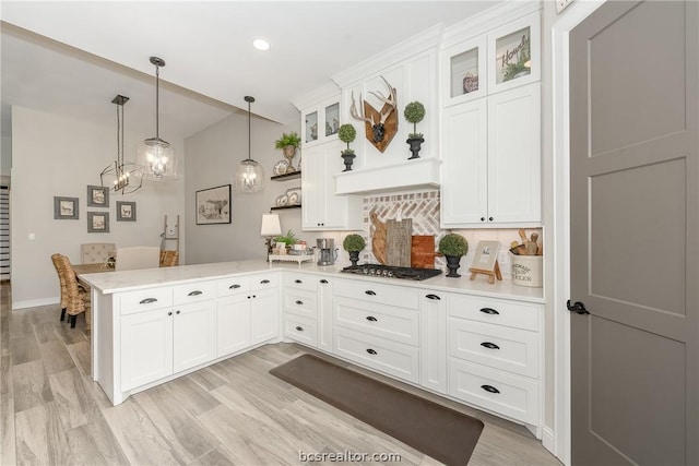 kitchen featuring kitchen peninsula, decorative backsplash, white cabinets, and hanging light fixtures