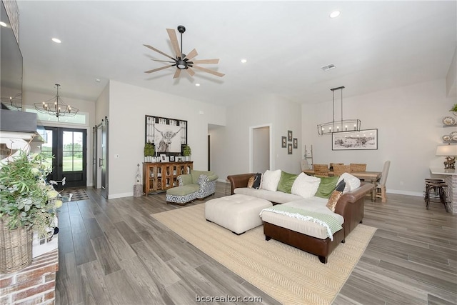 living room with hardwood / wood-style floors, ceiling fan with notable chandelier, and french doors