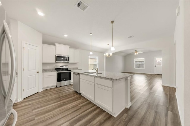 kitchen with a center island with sink, appliances with stainless steel finishes, sink, white cabinetry, and a healthy amount of sunlight