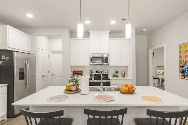 1326 Prairie Dr Unit 113, Bryan, TX 77803 - kitchen with appliances with stainless steel finishes, tasteful backsplash, a kitchen bar, light countertops, and white cabinetry