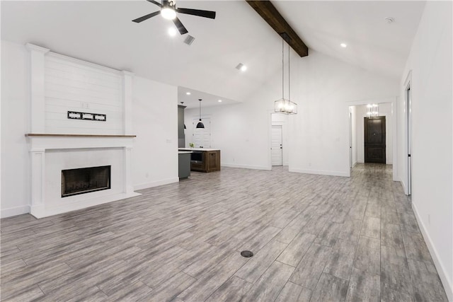 unfurnished living room with a large fireplace, ceiling fan, wood finished floors, high vaulted ceiling, and beam ceiling