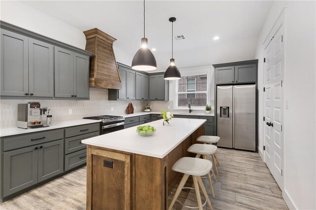 kitchen with pendant lighting, light countertops, appliances with stainless steel finishes, and a center island