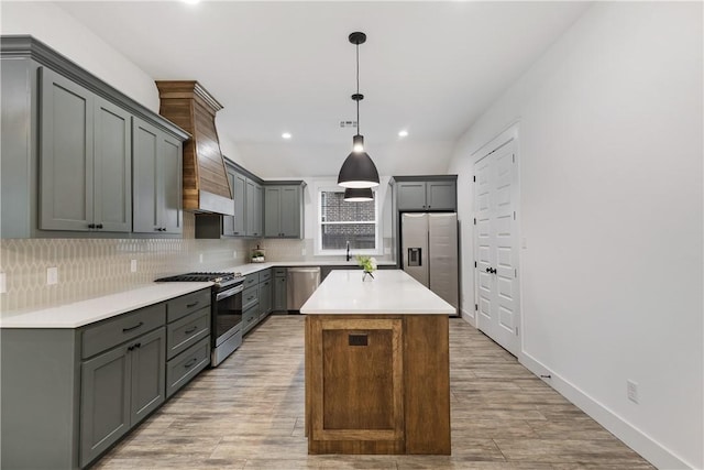 kitchen featuring appliances with stainless steel finishes, a center island, decorative light fixtures, gray cabinets, and light countertops