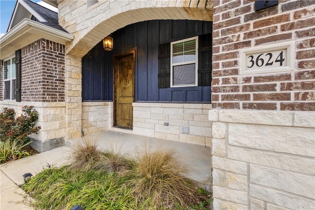 entrance to property with a porch and brick siding