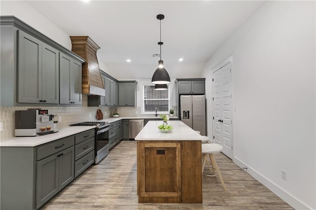 kitchen with stainless steel appliances, a kitchen island, hanging light fixtures, light countertops, and gray cabinets