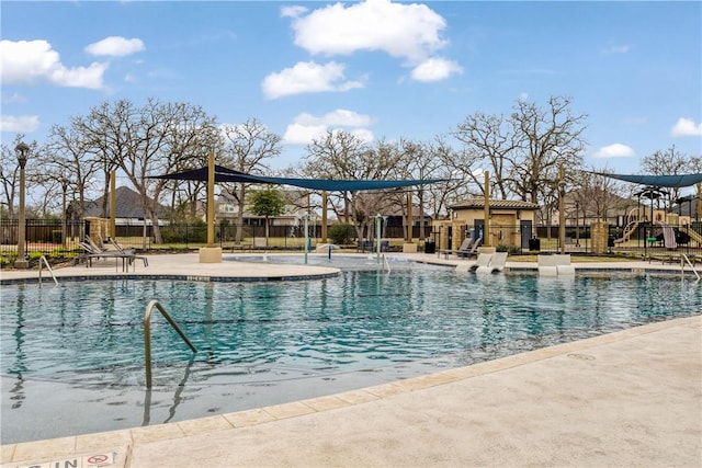 community pool featuring fence, playground community, and a patio