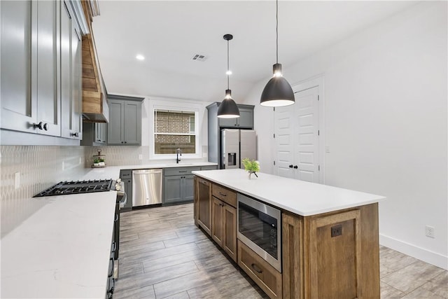 kitchen featuring light stone countertops, stainless steel appliances, a kitchen island, decorative backsplash, and pendant lighting