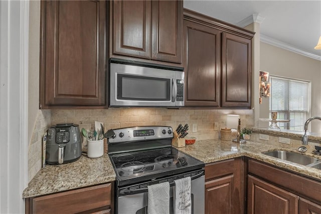 1611 Park Pl, College Station, TX 77840 - kitchen with appliances with stainless steel finishes, ornamental molding, decorative backsplash, light stone counters, and dark brown cabinets