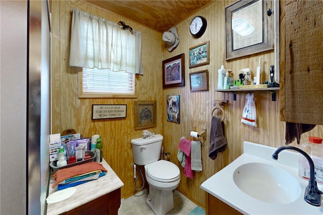 bathroom featuring tile patterned floors, vanity, wood walls, and toilet