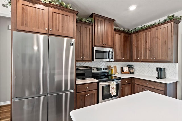 kitchen featuring recessed lighting, a toaster, stainless steel appliances, light countertops, and backsplash