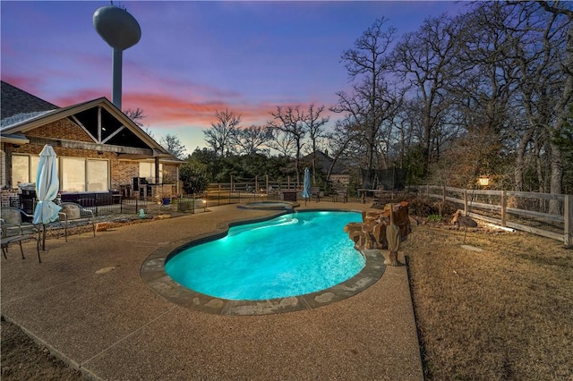 pool at dusk featuring a patio area and an in ground hot tub