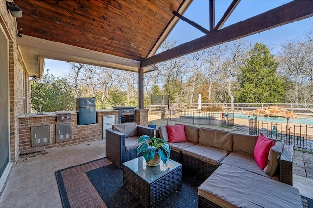 view of patio with a fenced in pool, outdoor lounge area, and exterior kitchen