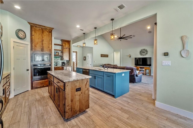 kitchen with hanging light fixtures, vaulted ceiling with beams, stainless steel appliances, a kitchen island, and light wood-type flooring