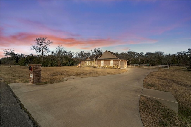 view of front of property featuring a garage, concrete driveway, and fence