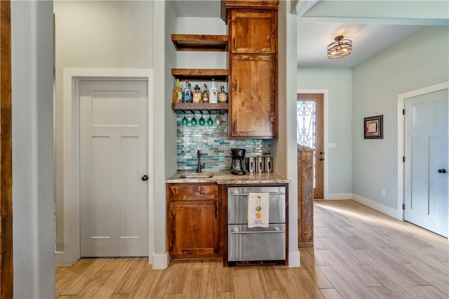 bar featuring sink, light hardwood / wood-style floors, and decorative backsplash