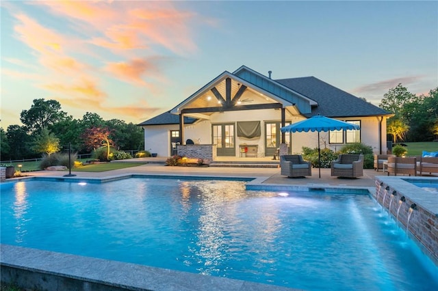 pool at dusk with an outdoor pool, an outdoor hangout area, french doors, and a patio