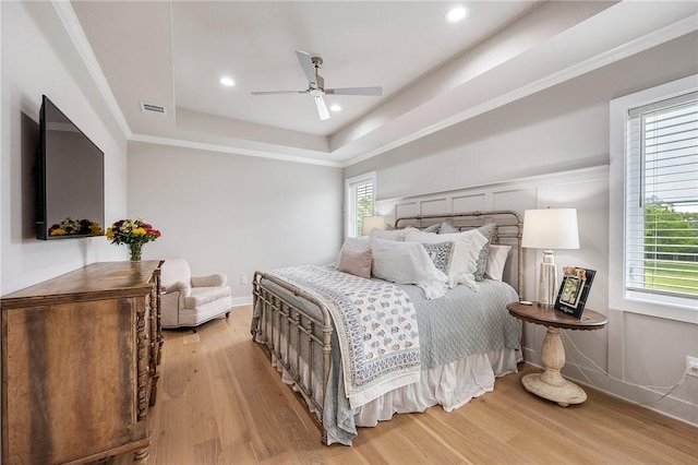bedroom with a ceiling fan, a tray ceiling, light wood finished floors, visible vents, and recessed lighting