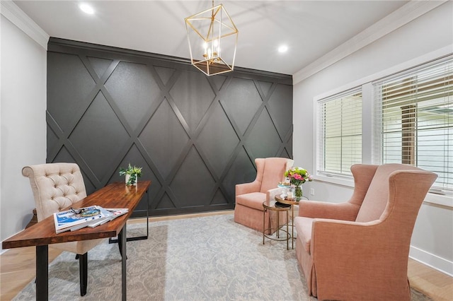 sitting room with a decorative wall, baseboards, ornamental molding, and an inviting chandelier