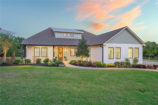 view of front of house with a lawn and roof with shingles