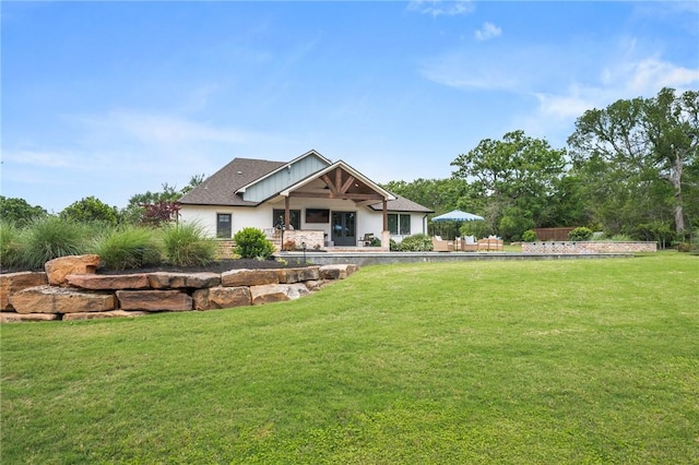 rear view of property featuring a lawn, a patio, and stucco siding
