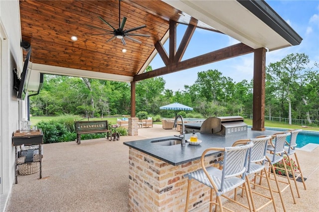 view of patio / terrace with a sink, outdoor wet bar, a ceiling fan, an outdoor kitchen, and an outdoor pool