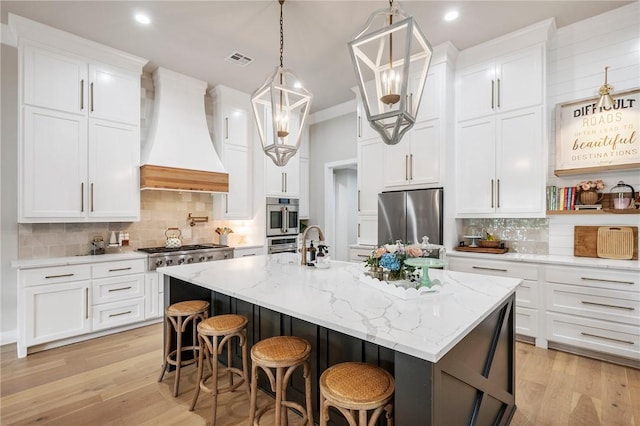 kitchen with visible vents, decorative backsplash, light wood-style flooring, appliances with stainless steel finishes, and custom exhaust hood