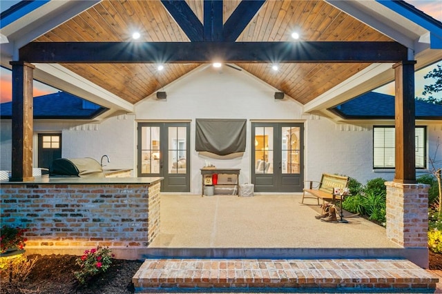 rear view of house with a sink, exterior kitchen, french doors, a patio, and brick siding