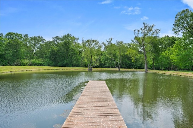view of dock with a forest view and a water view
