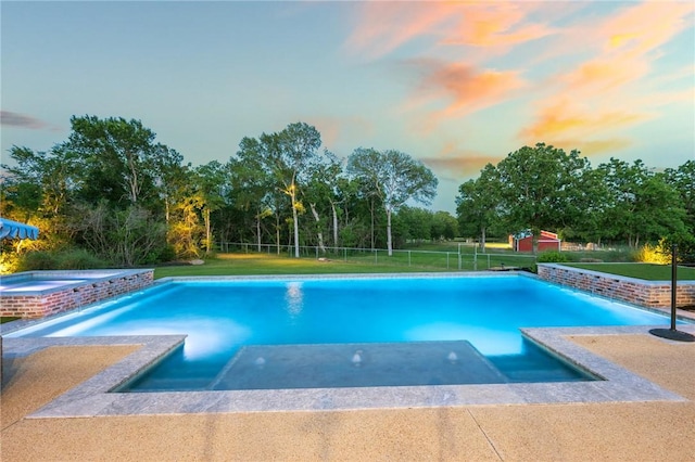 view of pool featuring a lawn, fence, a patio, and a pool with connected hot tub