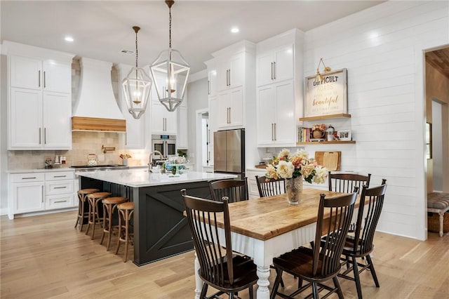 kitchen with decorative backsplash, custom exhaust hood, white cabinetry, and a breakfast bar