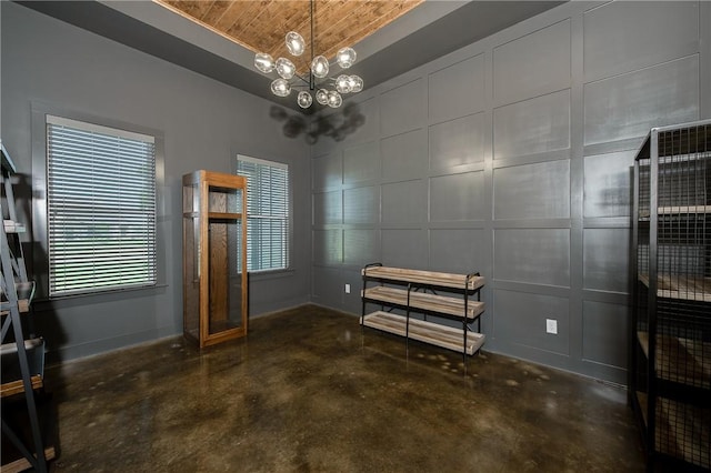 7532 Marys Way, Bryan, TX 77808 - unfurnished bedroom featuring concrete floors, a chandelier, baseboards, wood ceiling, and a decorative wall